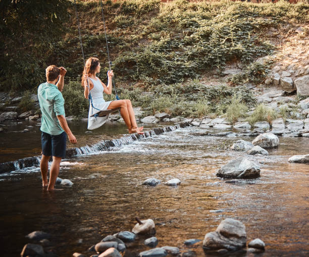 istock Couple have fun on swing over creek 1147569710