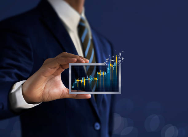 Business growth, progress or success concept. Businessman is holding a growing virtual hologram candlestick chart on dark blue background. stock photo