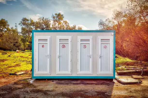 Photo of Prefabricated portable cabin with four numbered doors on a meadow field in the forest