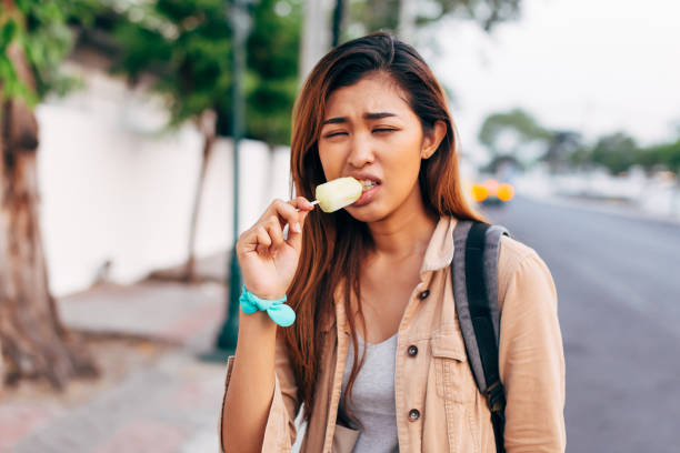 アイスクリームを食べながら傷ついている若いエスニック女性 - grief women selective focus outdoors ストックフォトと画像