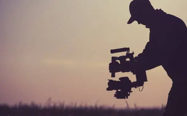 Video Production Concept. Silhouette of Gimbal Camera Operator. Picture Stabilization Device.