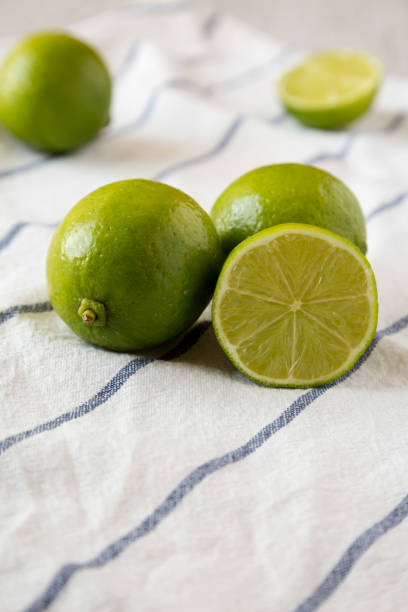 istock Whole and cut green citrus limes on cloth, side view. Closeup. 1147581699