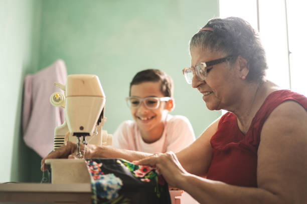 少年は彼の祖母の縫製を見 - owner embroidery small business indoors ストックフォトと画像