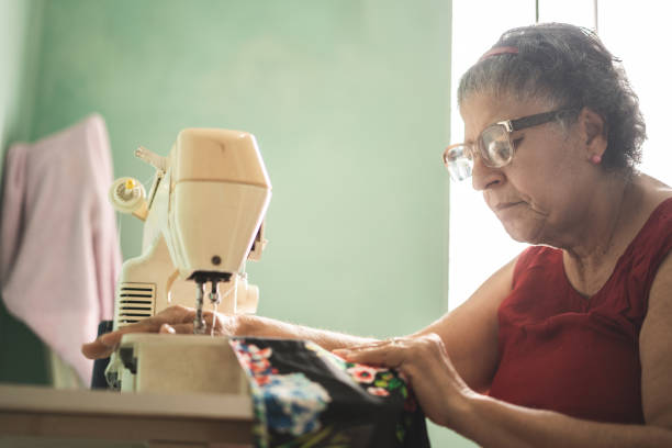 istock Senior woman stitching on sewing machine at home 1147587420