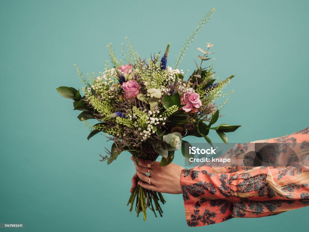 Woman holding a big bouquet of flowers Woman holding a big bouquet of flowers, arms only
Photo of hands and flowers in studio against turquoise Flower Stock Photo