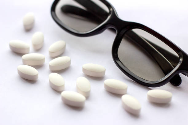 istock White pills and tablets with glasses on light background. Pharmacy and medicine concept. Focused on a pharmaceutical industry for eye diseases 1147597852
