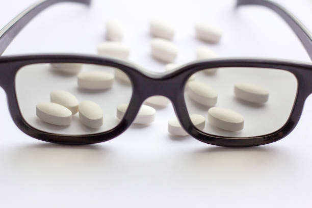 istock White pills and tablets with glasses on light background. Pharmacy and medicine concept. Focused on a pharmaceutical industry for eye diseases 1147597873