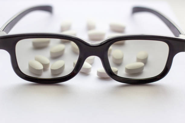 White pills and tablets with glasses on light background. Pharmacy and medicine concept. Focused on a pharmaceutical industry for eye diseases