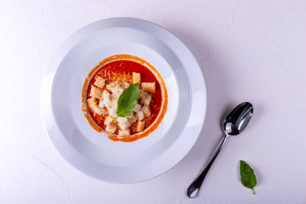 istock Tomato cream soup with crackers in a white plate on a white background. 1147599019