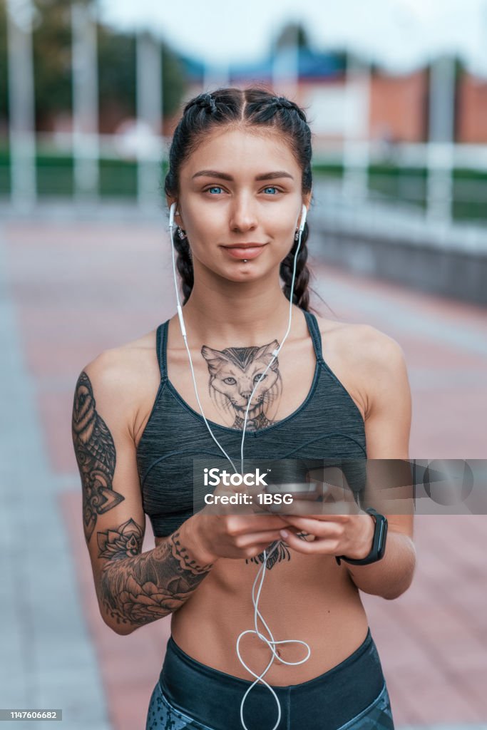 Beautiful Woman Smiling Happy Girl In Summer In City Tanned Skin Tattoo  Sportswear Top Phone Earphones Concept Of Strength Femininity Courage  Confidence Thoughts Of Inspiration Motivation Stock Photo - Download Image  Now -