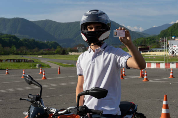 joven en un casco en la moto está mostrando licencia de conducir - ciclomotor vehículo de motor fotos fotografías e imágenes de stock