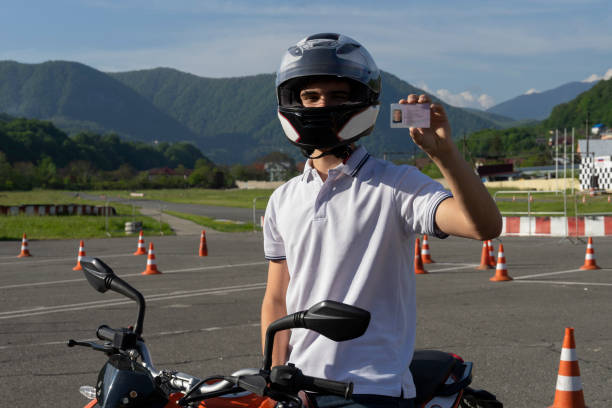 giovane con un casco in moto mostra la patente - driving test foto e immagini stock