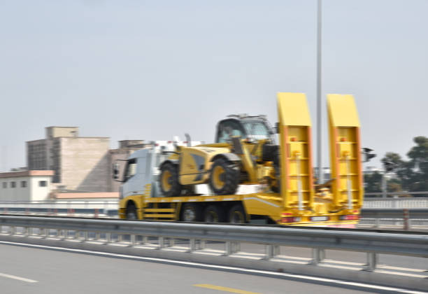 construction machinery carrier on the highway construction machinery carrier on the highway Hauling Trailers for heavy construction machineries stock pictures, royalty-free photos & images