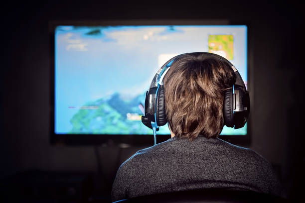 o menino pequeno caucasiano do gamer que desgasta um auriculares joga o jogo video. vício em videogames. - video game child playing leisure games - fotografias e filmes do acervo