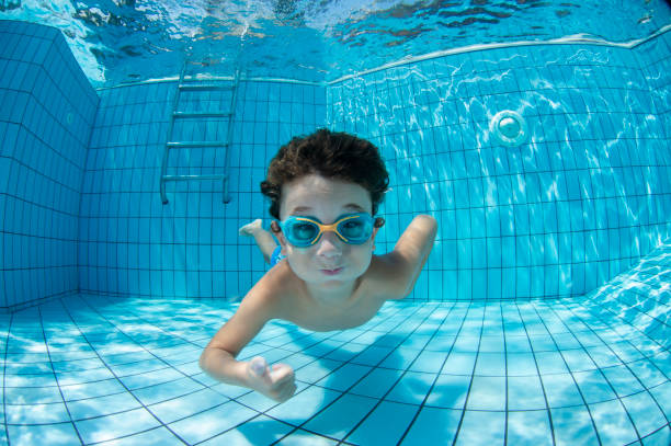 unterwasser-jungwierspaß im schwimmbad mit brille - schwimmen stock-fotos und bilder