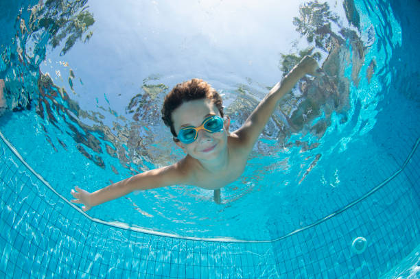подводный молодой мальчик fun в бассейне с очками - swimming стоковые фото и изображения