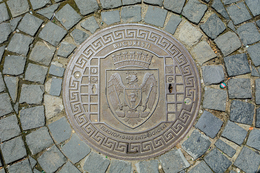 Prague, Czechia - September 18, 2022:  Manhole sewer cover on the cobblestone sidewalk stone brick of the streets of Prague Czech Republic Czechia