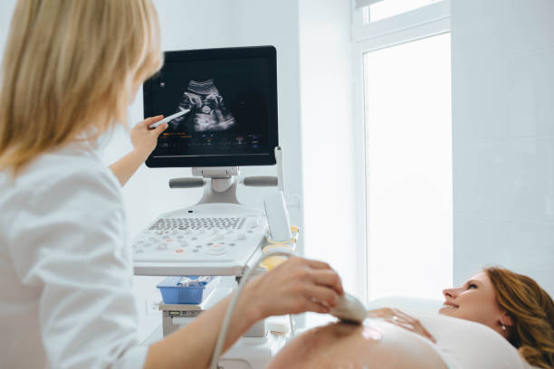 Pregnant woman having sonogram at clinic. pregnant patient ultrasound exam Happy woman looking at ultrasound results with her doctor in examination room ultrasound photos stock pictures, royalty-free photos & images