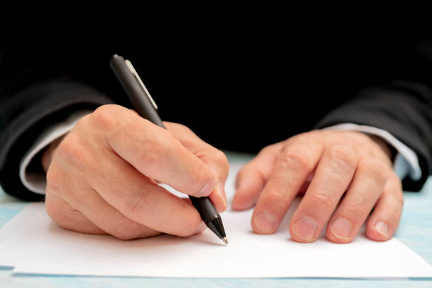 istock A pen in a man's hand. White sheet of paper. 1147613384