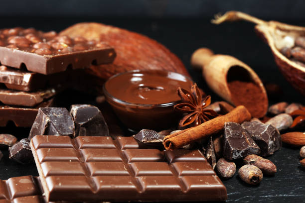 istock Melting chocolate or melted chocolate with a chocolate swirl and stack, chips and powder on black 1147615902