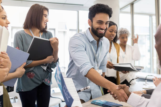 Middle Eastern man meets Expo speaker After waiting in line, a mid adult Middle Eastern man finally gets to meet the Expo speaker and get his autograph. global business handshake stock pictures, royalty-free photos & images