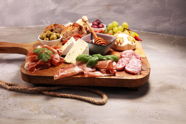 istock Cutting board with prosciutto, salami, cheese,bread and olives on dark stone background 1147617185