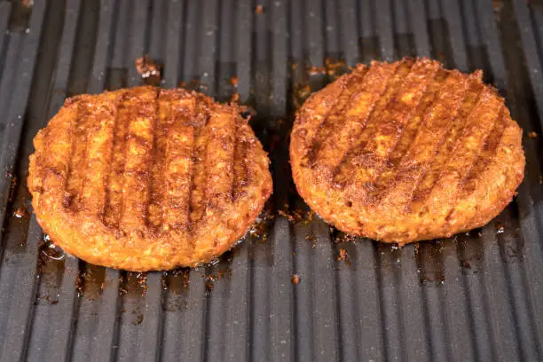 Photo of Close up of plant based burger patties on griddle being grilled