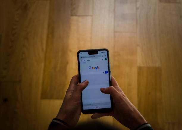 A woman using a Google Pixel 3 Xl  at home . A close up shot of a person using the google pixel phone in a canid scene against a clean background. google brand name photos stock pictures, royalty-free photos & images