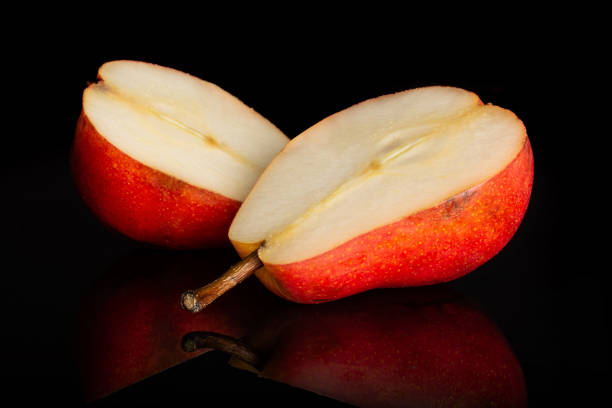 Group of two halves of fresh red pear isolated on black glass