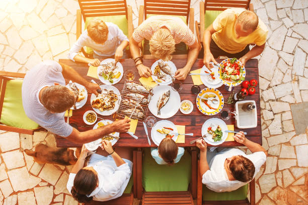 big miltigeneration family dinner in process. top view vertical image on table with food and hands - foods and drinks clothing garment household equipment imagens e fotografias de stock