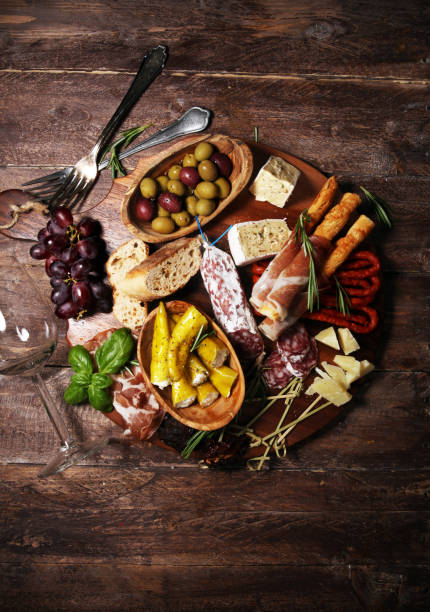 istock antipasto various appetizer. Cutting board with prosciutto, salami, cheese, bread and olives on dark wooden background 1147630189