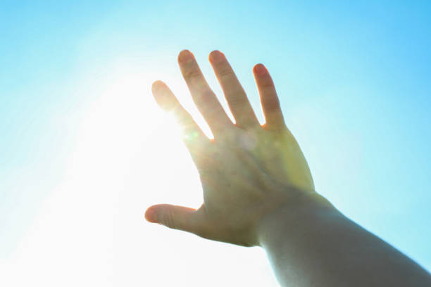 Langit biru yang indah dan latar belakang matahari dengan tangan wanita. Langit yang indah foto stok