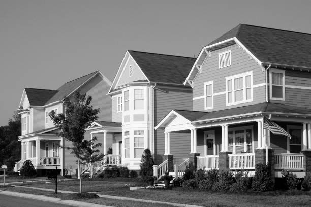 Traditional Victorian, Cottage Style Homes in a Residential Neighborhood captured in black and white McAdenville, North Carolina, USA - July 9, 2012: The American Dream is pictured in this iconic image of a row of new, Victorian-style homes in the McAdenville neighborhood development. Most American homes are now built on smaller lots with sidewalks and tree-lined streets in the suburbs of large cities. Traditional architectural styles blend with modern amenities, fixtures and details. monochrome house stock pictures, royalty-free photos & images