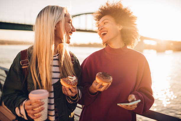 istock Girls eating donuts and smiling 1147635790