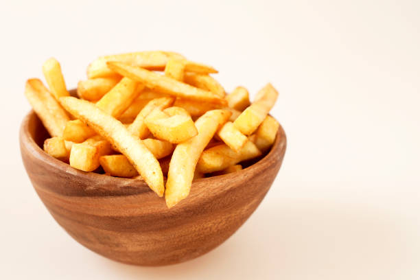 fried potato in wooden bowl over white background