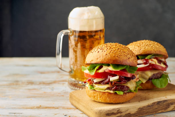 two big burgers and pint of beer on old wooden table - beer hamburger american culture beef imagens e fotografias de stock