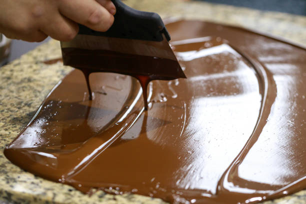 istock Chocolatier with a spatula is stirring the tempered liquid chocolate on a granite table 1147640423