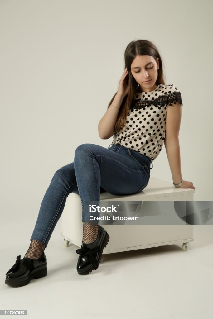 Full-length portrait of a beautiful young woman in the studio wearing polka dots blouse and jeans Adult Stock Photo