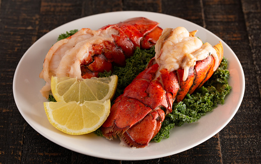 Two Broiled Lobster Tails on a Bed of Kale with Lemon Slices