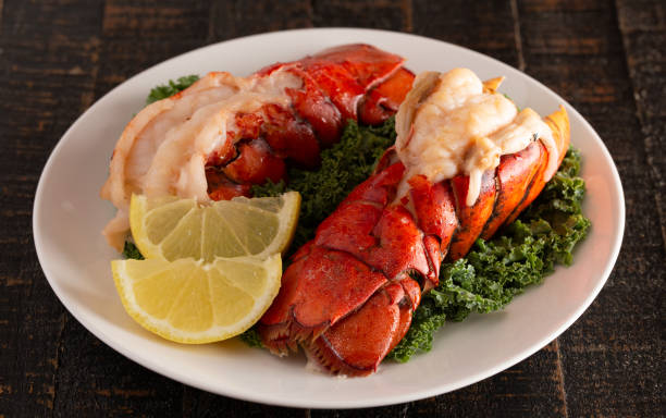 Two Broiled Lobster Tails on a Bed of Kale with Lemon Slices stock photo