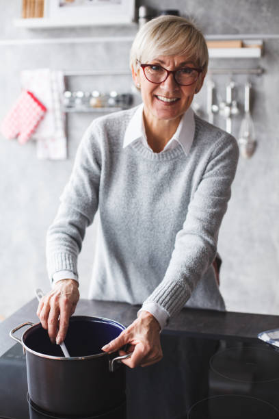 istock Smiling senior woman cooking lunch 1147655765