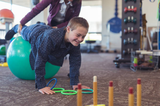 ein junge macht workouts mit einem ergotherapeuten in einer physiotherapie-klinik - physical and occupational therapists stock-fotos und bilder