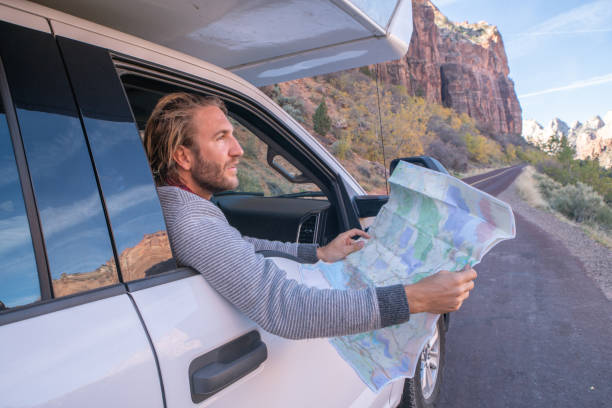 istock Road trip concept; Young man inside camper-van looking at road map for directions exploring national parks and nature ready for adventure. 1147670368