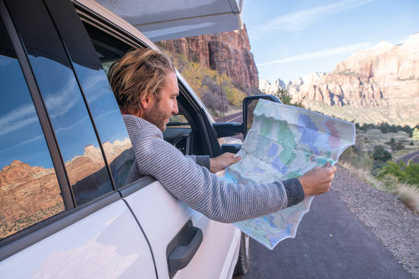 istock Road trip concept; Young man inside camper-van looking at road map for directions exploring national parks and nature ready for adventure. 1147674101