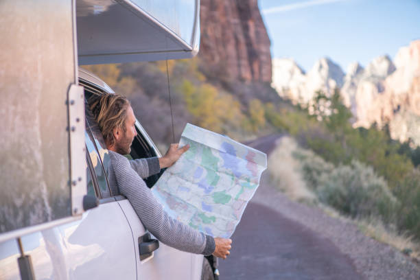 istock Road trip concept; Young man inside camper-van looking at road map for directions exploring national parks and nature ready for adventure. 1147674902