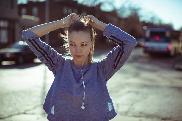 Getting Ready Close up of a woman tying her hair before jogging woman tying hair in ponytail getting ready for exercising stock pictures, royalty-free photos & images