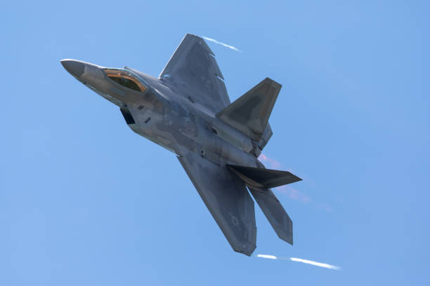 vista ravvicinata di un f-22 raptor in una manovra ad alta g, con sentieri di condensazione che si formano sulla punta delle ali e postbruciatori - fighter plane jet military airplane afterburner foto e immagini stock