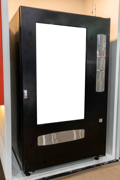 Vending machine for snacks in black metal color scheme on white wall background.
