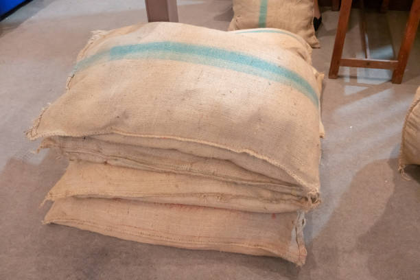 pile of burlap sacks with green stripe on concrete floor. agriculture concept. - gunny sack imagens e fotografias de stock