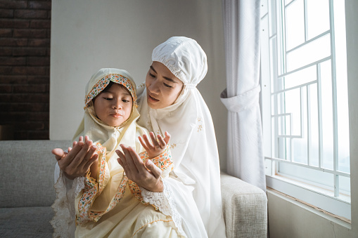 mother teach her daughter to pray with her hand open palm
